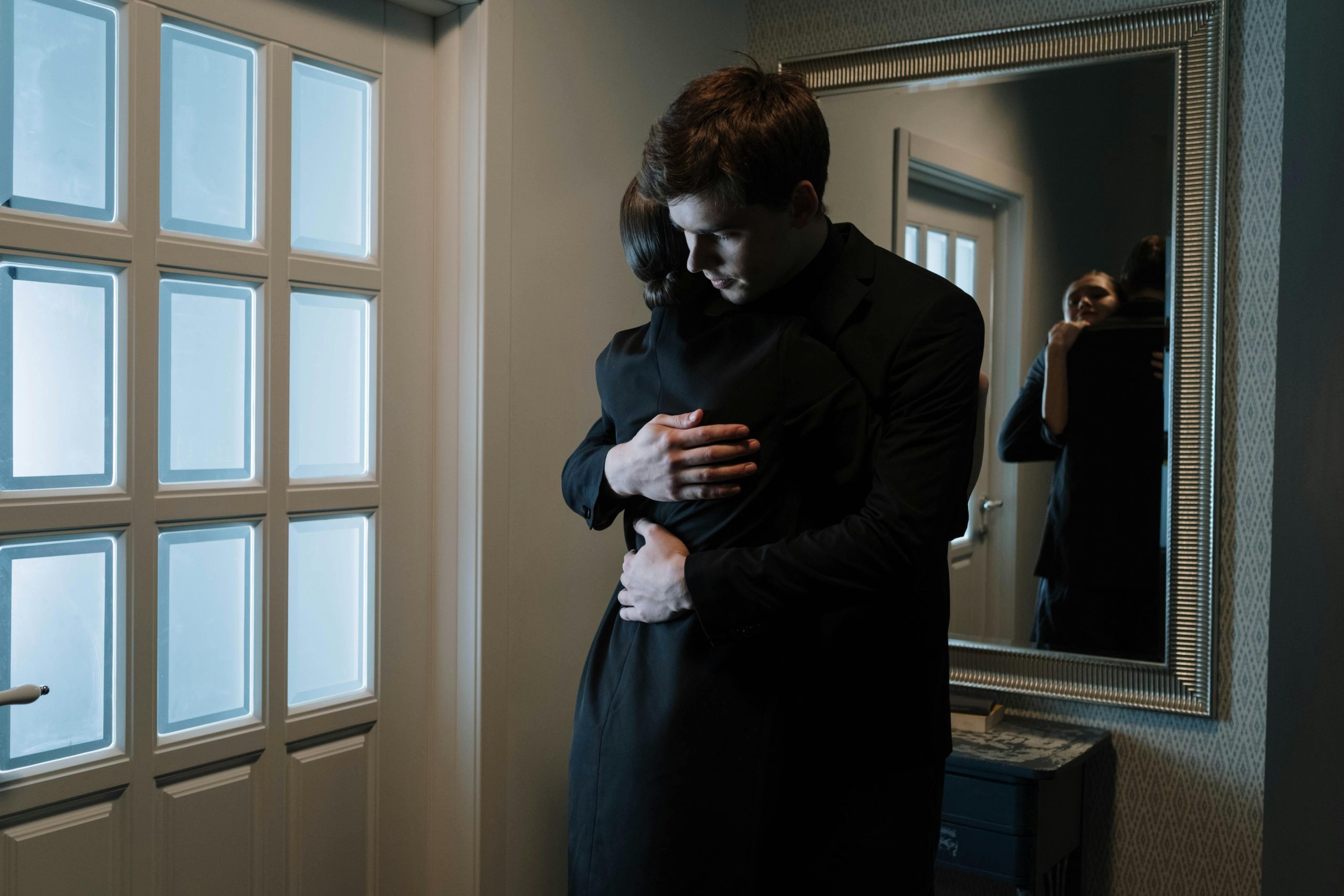 A couple shares an emotional embrace indoors, reflecting intimacy and support.
