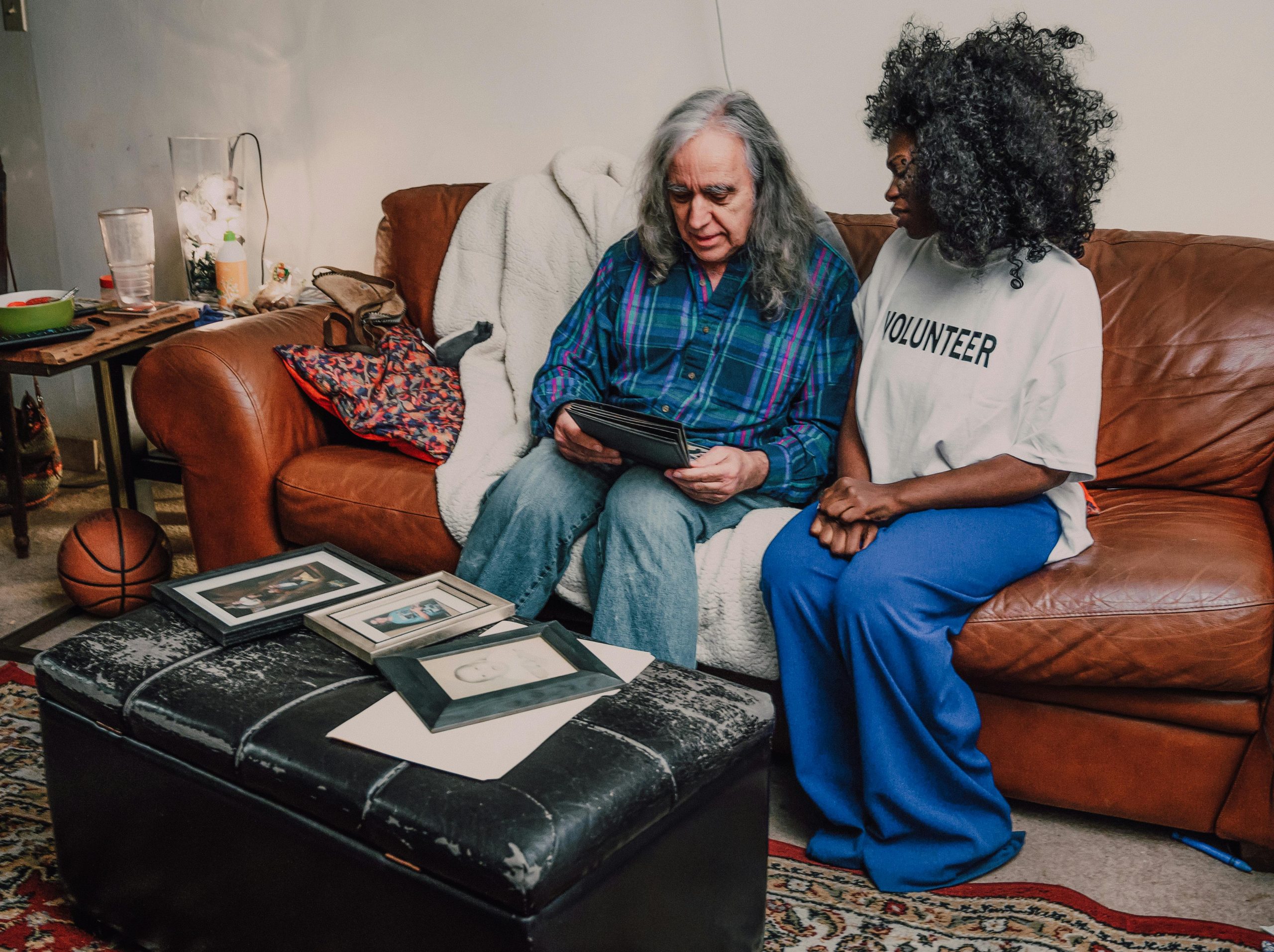 An emotional bonding scene between volunteers on a cozy sofa with family photos.