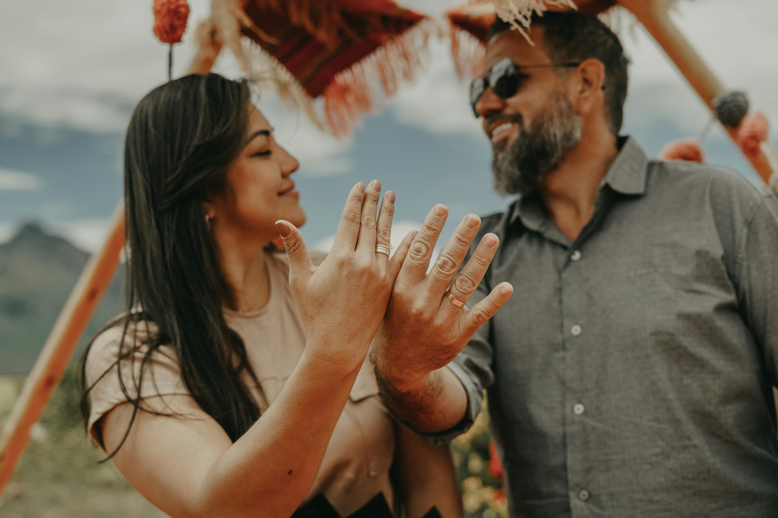 A happy couple in the beautiful Maras, Peru, displaying their wedding rings outdoors.